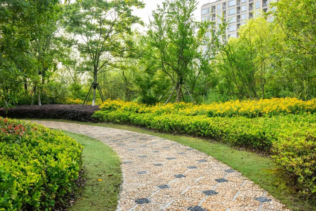 Curved gravel path through a lush green park with yellow flowers and trees in Columbus, GA.